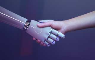 Human hand shaking hands with a robotic hand.