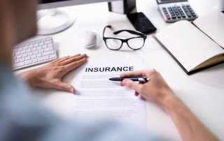 Person reviewing an insurance document at a desk with office supplies.