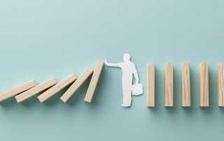 Figure stopping falling dominoes, symbolising crisis prevention and control.