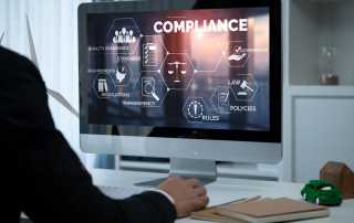 Professional reviewing compliance dashboard on screen illustrating compliance by design in customer communications.